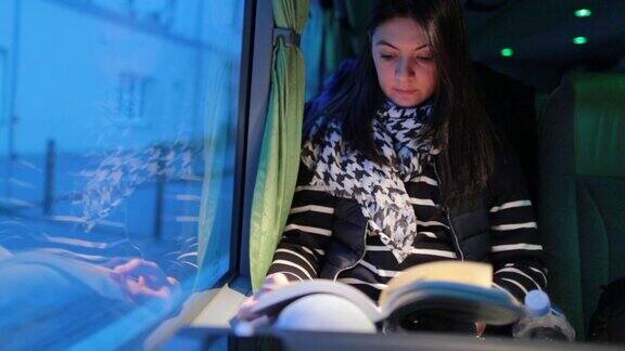 5.一名女子在晚上旅行的公交车上看书
