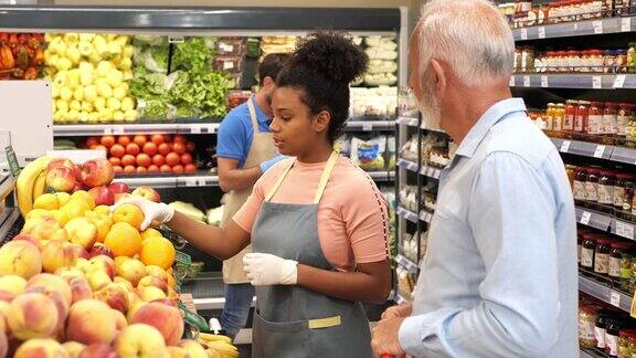 美国员工在超市协助顾客购买水果和蔬菜