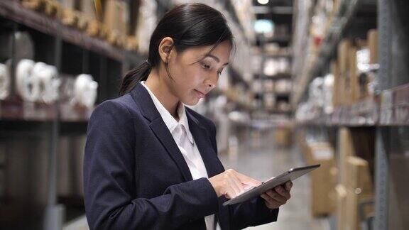 智能仓库管理:商务亚洲女性手握数字平板电脑在仓库