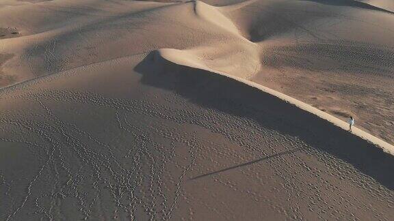 鸟瞰图-一个孤独的女孩走过沙漠日落时长长的阴影马斯帕洛马斯大加那利岛