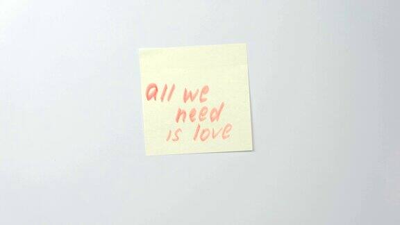 特写女人的手贴黄色贴纸纸上的字我们需要的是爱