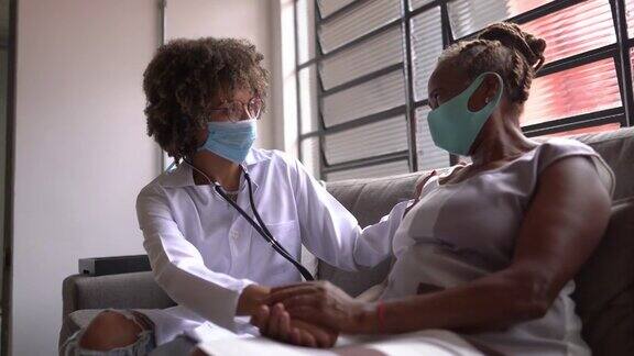 医生在家访中安慰成熟的病人-使用口罩