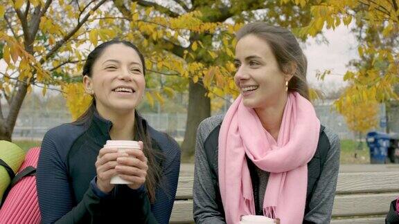 成年女性朋友在公园长椅上喝咖啡