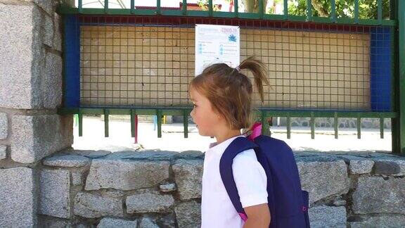 一个金发小女孩背着蓝色背包去上学学校