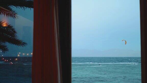人们风筝冲浪在埃及达哈卜美丽的清澈的水从窗口的观点探索蓝色的大海以山脉为背景人们风筝冲浪慢镜头4k