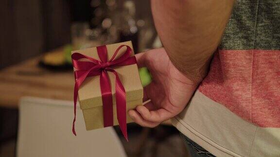 一个男人拿着一个背后系着红丝带的礼品盒