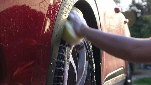 特写的一个女人的手洗合金车轮的汽车海绵和肥皂上洗车用白色肥皂手动洗车洗车服务理念