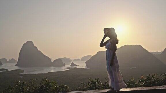 一名女游客站在山顶欣赏令人叹为观止的日落美景