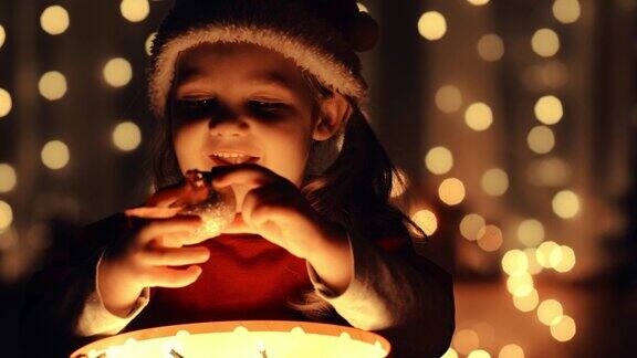小女孩从一个发光的礼品盒里拿出一个圣诞装饰品