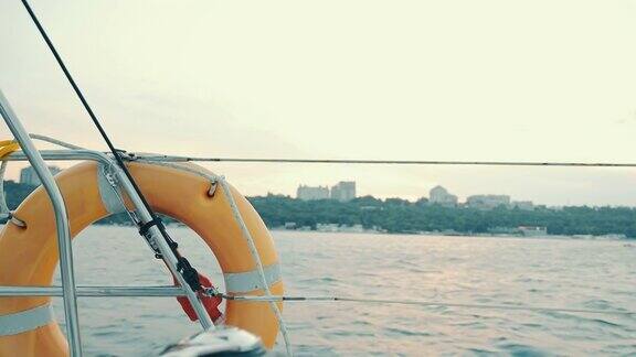 在阴天日落时从游艇上眺望大海从游艇上俯瞰地平线上的城市游艇上的救生圈
