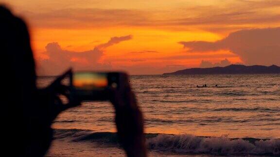 年轻的女游客在海滩上用智能手机拍摄海景的特写