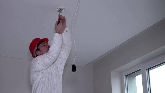 男电工在天花板上安装感烟报警器