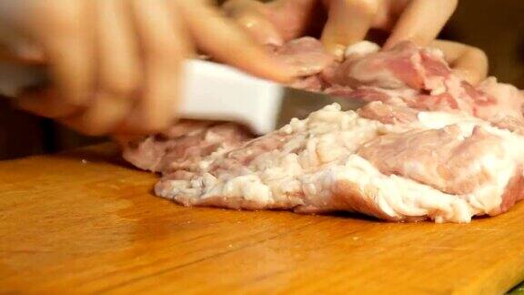 女人在砧板上用刀把肉切成小块