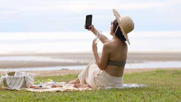 愉快的年轻女子与野餐的东西在海边拍照