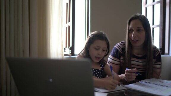 母亲在家里用笔记本电脑帮助女儿学习