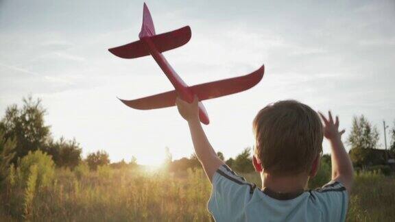 一个小男孩在田野里跑着手里拿着一架粉红色的玩具飞机