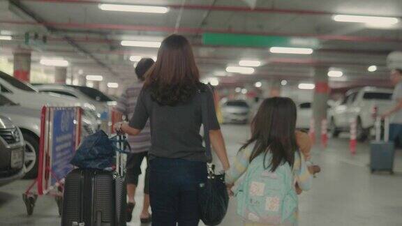 一个亚洲女人和一个带着行李箱的女孩在停车场