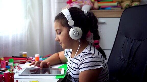 美丽的女孩与耳机使用数字平板电脑