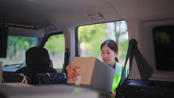 女送货员从货车上取纸箱送货