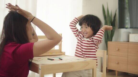 亚洲男孩做家庭作业在早上和妈妈