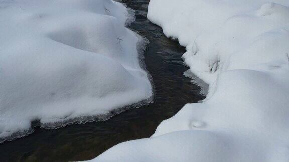 冬天的风景近距离观察从山间流淌的河水融化着深深的白雪背景