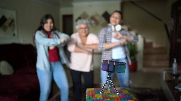 祖母和孙女在家里用手机在视频博客或社交媒体上跳舞和录音
