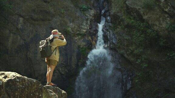 女游客用手机拍摄瀑布