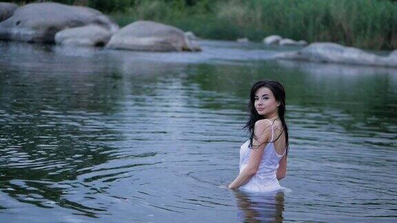 美丽的黑发长发女孩站在水里缓慢的运动