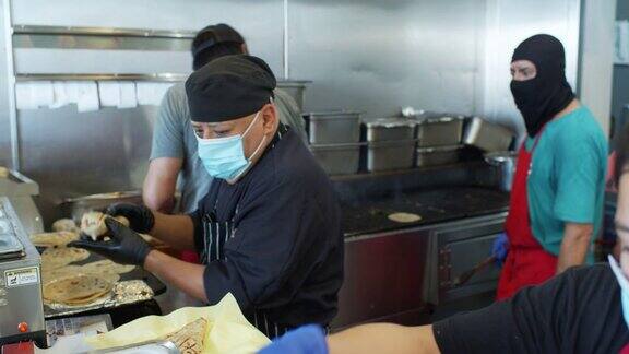 在Covid-19封锁期间厨师在工作时戴着口罩和手套烹饪墨西哥菜