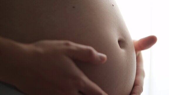 孕妇的手抚摸肚子的宏观特写