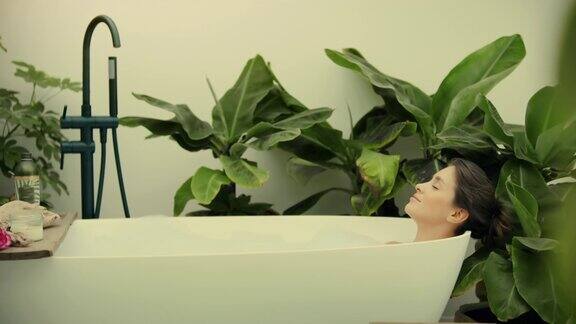 一个年轻的女人正在她的浴室里郁郁葱葱的绿色花园里泡澡