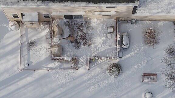 一名成年男子在一场冬季降雪后用铁铲清理门廊上的积雪鸟瞰直接上方的无人机慢动作视频