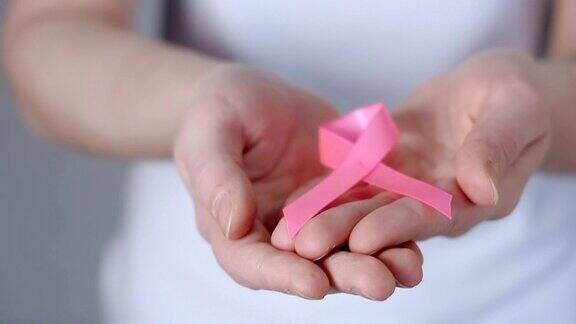 妇女手举粉色乳腺癌意识丝带-乳腺癌意识概念