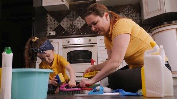 母亲和女儿打扫房子她们坐在地板上打扫地板