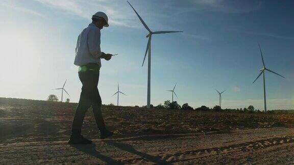 在风力发电厂工作的年轻男工程师的剪影日落检查风力发电厂的能源生产可再生能源工厂