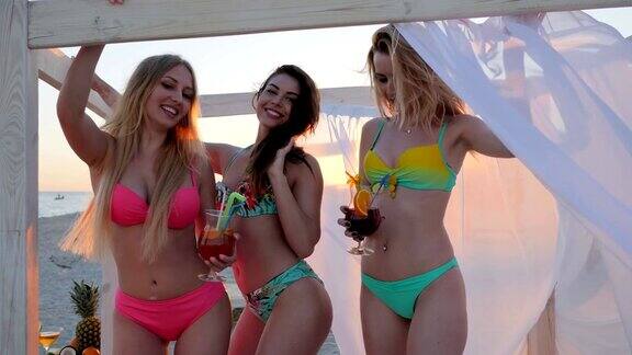海滩派对在海滩上的平房愉快的女朋友热带水果在女孩的手中
