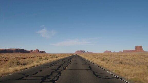 在一个阳光明媚的日子里开车穿过纪念碑谷的热沙漠