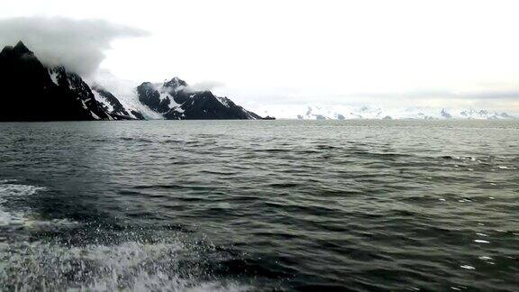 帽带企鹅站在美丽的蓝色海水和冰山旁