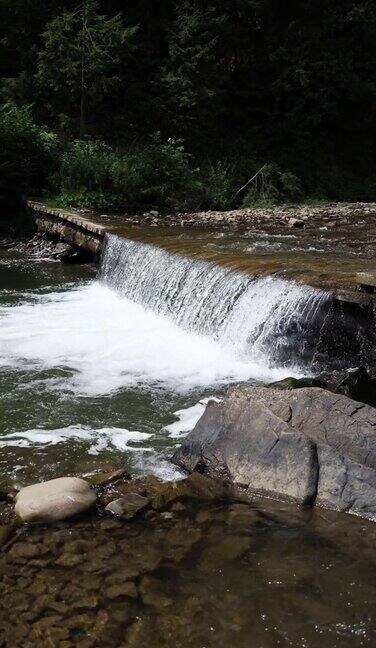 在夏天的森林背景下山上河流上的小瀑布垂直视频