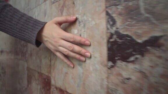女人的手摸着粉红色的大理石墙