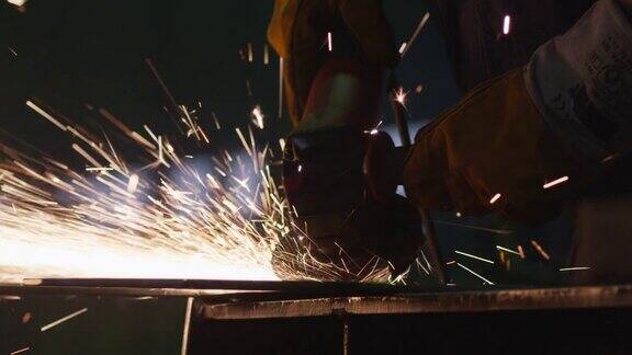 在一个工厂的重工业工人正在一个角磨床上与金属工作而热火花产生的结果