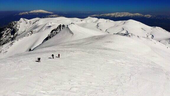 无人机拍摄成功的登山队伍在冬季在高海拔雪山峰顶的山脊上排排攀登