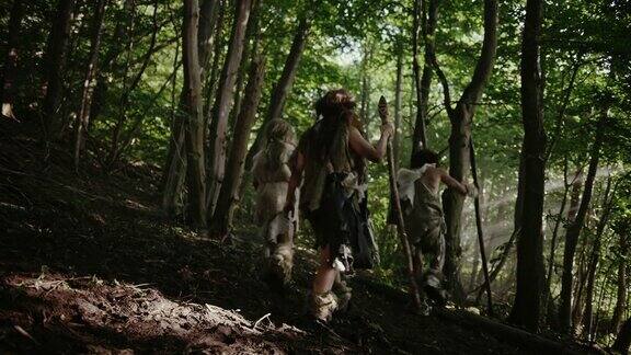 部落的狩猎-采集者戴着动物皮拿着石头尖端的工具探索史前森林狩猎动物猎物穴居人家族在丛林中狩猎或迁徙以下观点