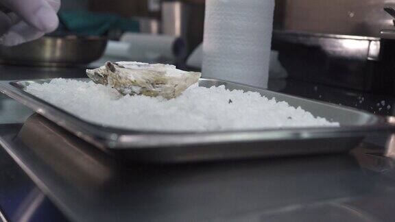 厨房里一名男子将牡蛎放在装有碎冰的金属托盘上