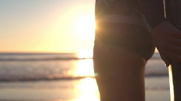 一个女孩站在沙滩上微笑她背上有一块冲浪板