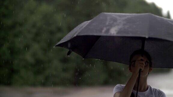 女孩在雨天里捻着伞看着雨点打在伞上秋天的心情慢动作
