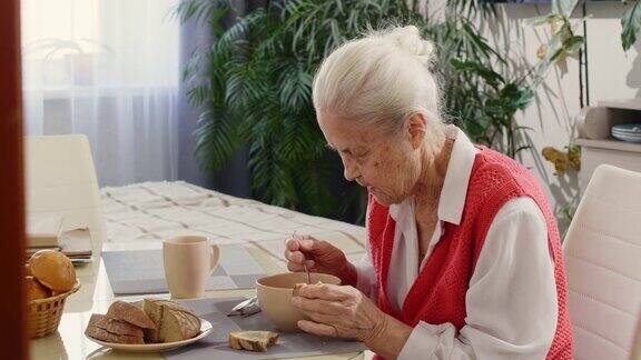 在家里吃汤和面包的老妇人