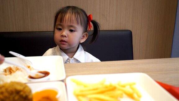 小女孩在快餐店吃炸鸡和炸土豆