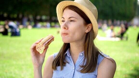 饥饿的女人在公园吃法棍面包游客在公园享用午餐享受夏日的阳光