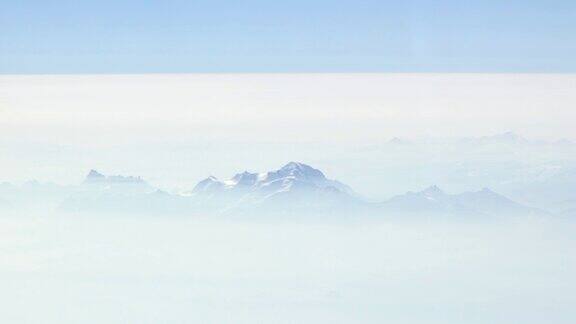 透过飞机窗口从上空俯瞰山脉和云朵